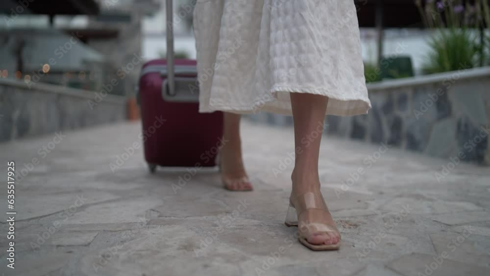 Toma detalle de pies andando con maleta de viaje en piscina de hotel