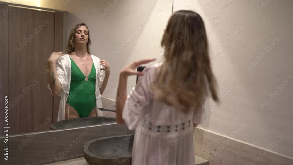 chica joven en bañador verde mirándose en espejo de vestuario