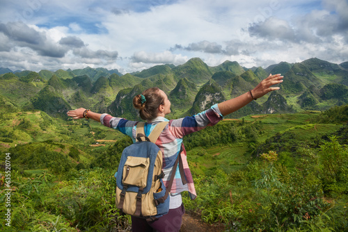 Happy and joyful woman traveller with raised hands enjoying view mountains in Norh Vietnam.