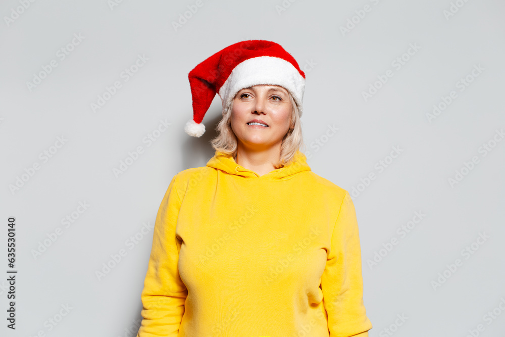 Studio portrait of woman in yellow sweater wearing Santa hat on white background. Studio portrait of woman in yellow sweater wearing Santa hat on white background.
