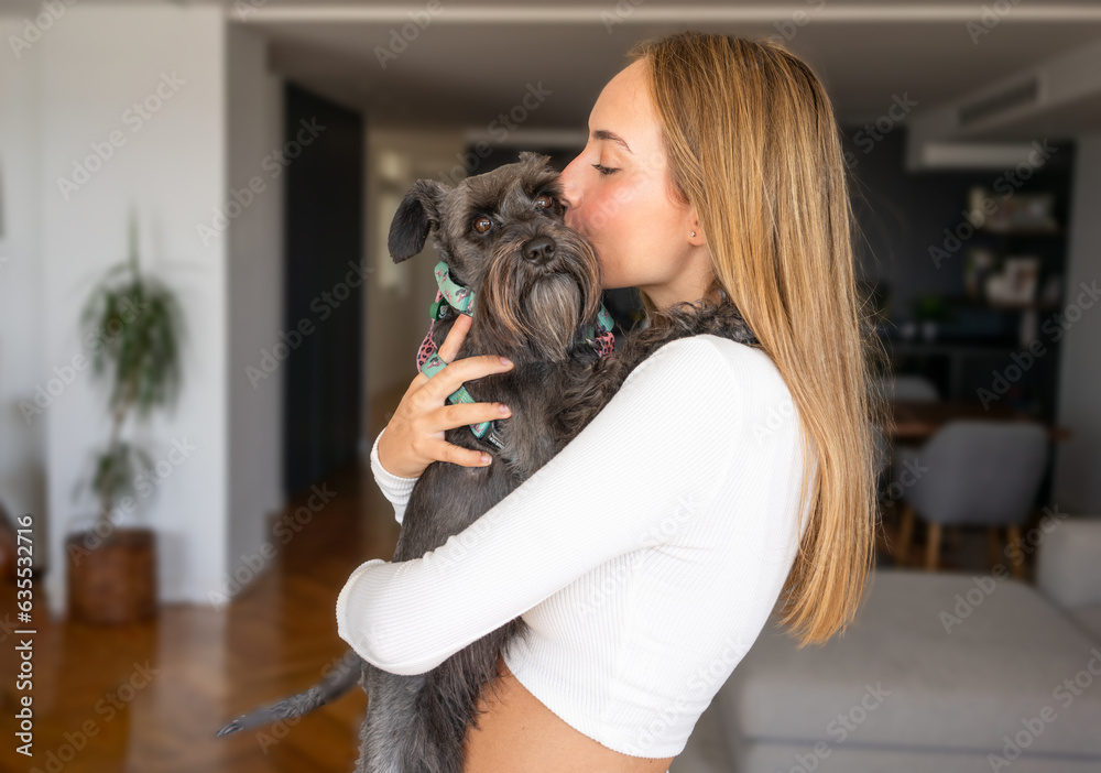 Teen girl hugging her schnauzer god at home. Teen girl hugging her schnauzer god at home.