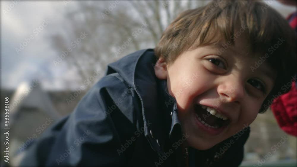 Excited child smiling while circling on roundabout at playground during fall season, close-up face of small boy feeling excitement and happiness Excited child smiling while circling on roundabout at playground during fall season, close-up face of small boy feeling excitement and happiness