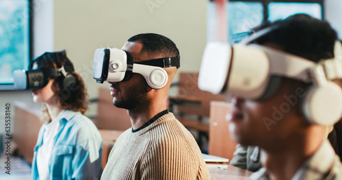 Close up of mixed-races males and female students in VR glasses sitting at college and listening to lection. Hi-tech studying. Multiethnic young people having virtual reality learning experience.