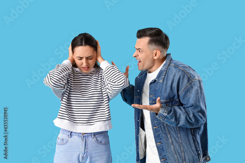 Photography Young couple quarreling on blue background