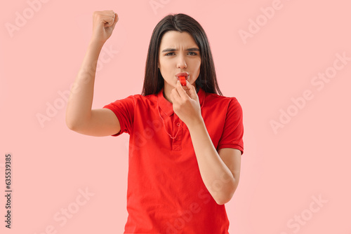 Female lifeguard whistling on pink background