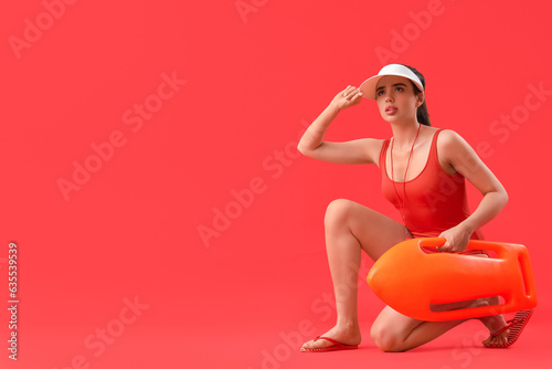Female lifeguard with rescue buoy on red background