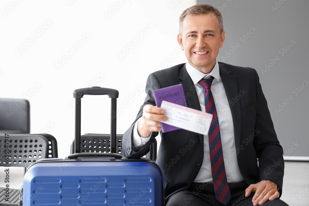 Mature businessman with ticket and passport in hall of airport Mature businessman with ticket and passport in hall of airport