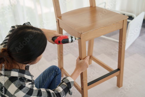 Asian woman assembles furniture by herself at home