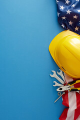 Embrace the American national holiday: Labor Day. Top view vertical shot of american flag, safety helmet, tools on blue background with empty space for advert or text
