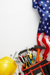 Commemorate Labor Day with a vibrant banner. Top view vertical shot of american flag, tools bag organizer, safety hard hat on white background with empty space for promo or text