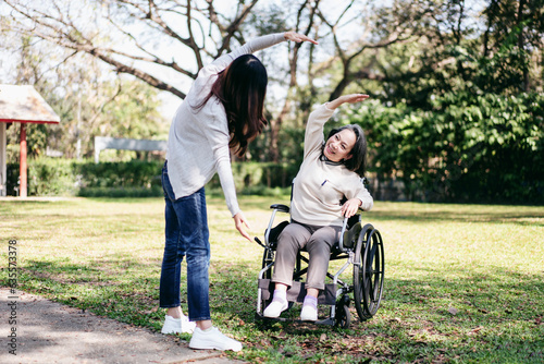 Senior on wheelchair and daughter family concept, Young asian woman exercise with mother on wheelchair in the garden while senior woman and daughter relaxation with enjoying together