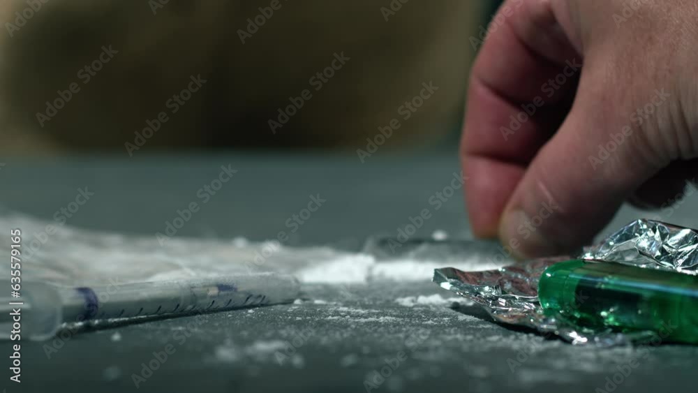 Drug addict preparing lines of heroin for injection