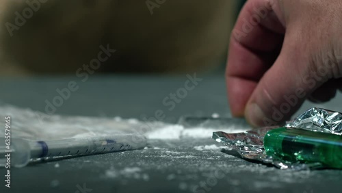 Drug addict preparing lines of heroin for injection