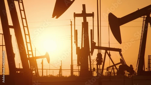 The sun rises behind a large oil field in California.