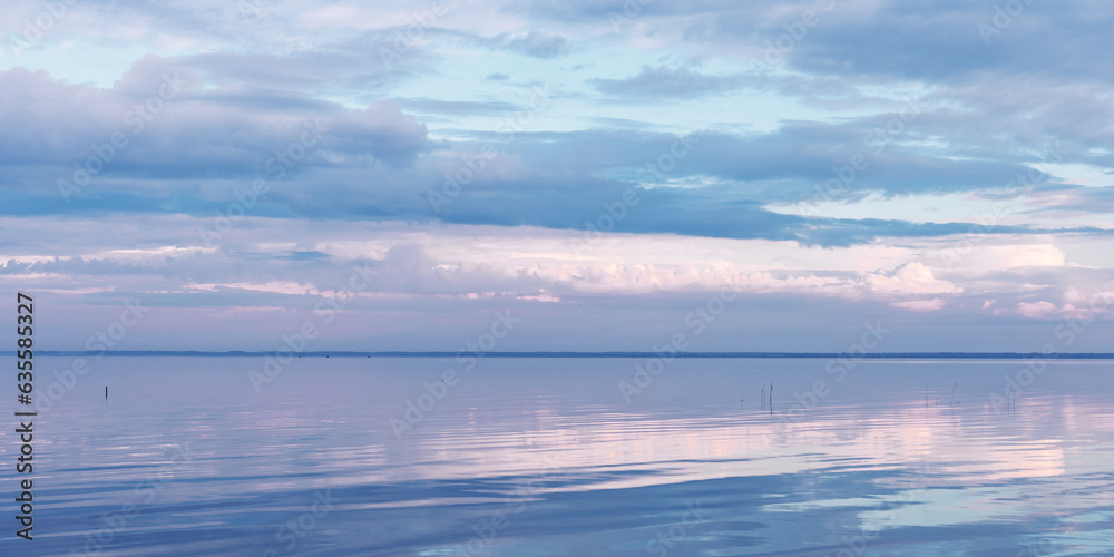 Fototapeta premium Nature picturesque landscape, clouds reflected on water surface, windless summer weather, purple blue trend sky background, mirroring sky on water, white blue nature gradient, aesthetic banner