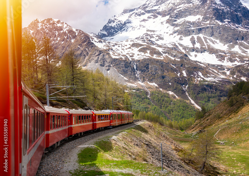 Red train moving in beautiful green summer forest in Switzerland