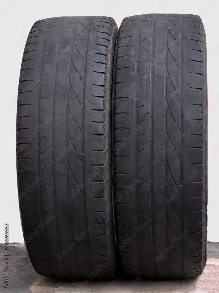 two old tires with worn treads arranged side by side on a white background.