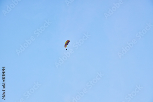 Paraglider silhouette flying in the blue sky.