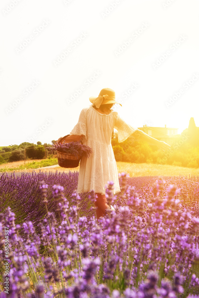 Girl in white dress and hat with basket walking in lavender field