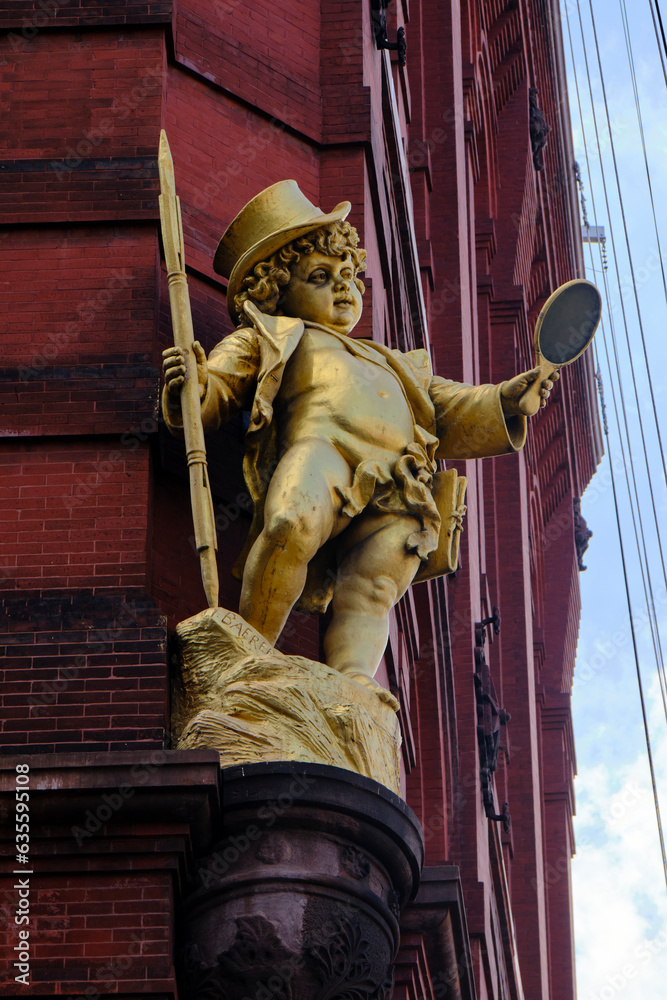 Obraz premium golden statue of a boy against a old brick building