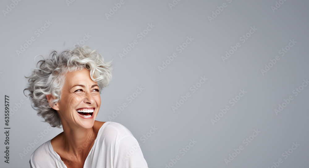 Beautiful gorgeous 50s mid age beautiful elderly senior model woman with grey hair laughing and smiling. Mature old lady close up portrait.