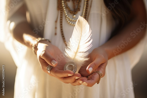 Woman with boho jewellery holding a feather in her hands close up