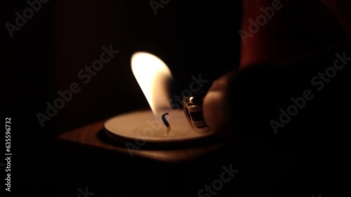 Close-up of flame burning on the candle isolated on a black background. Lighting wick with lighter