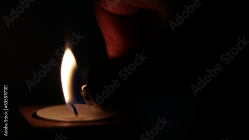 Close-up of flame burning on the candle isolated on a black background. Lighting wick with lighter