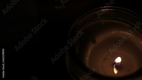 Closeup Of Flickering Candle Flame In Transparent Jar - High Angle Shot. Close-up of the flame burning on candle, isolated on a black background. Candle flame in dark