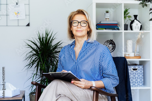 Professional Psychotherapy. Successful female Psychologist Smiling To Camera Sitting On armchair In Office. Mature 50s middle-age professional portrait of teacher, coach, mentor, therapist, counselor