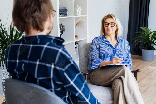 Professional psychotherapy. Female psychologist having session with male patient at mental health clinic, Taking Note During Appointment In Office. Psychological help service. Treatment of depression