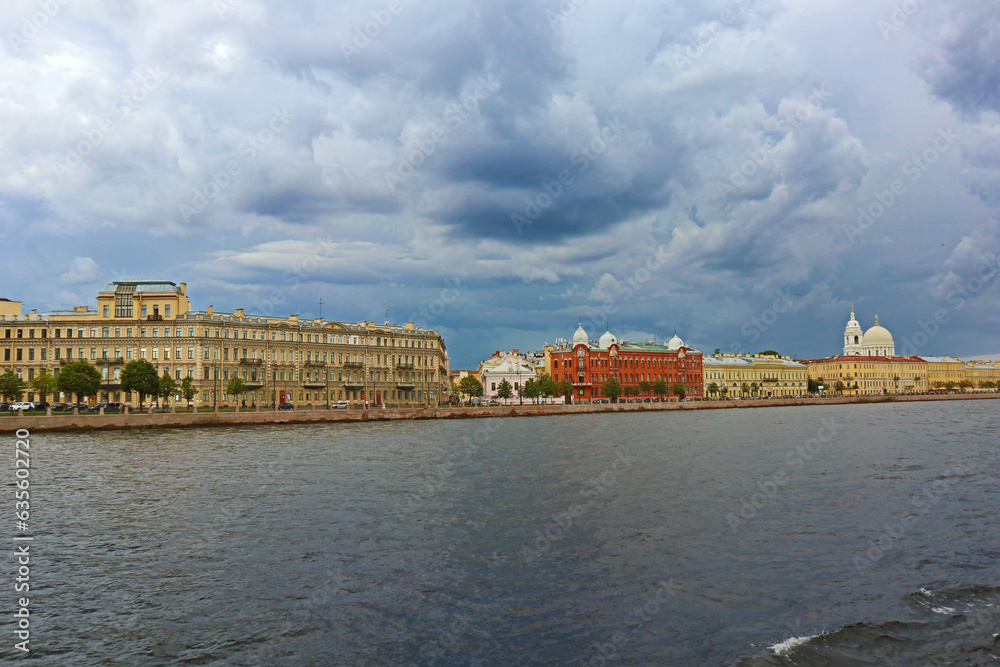Summer landscape with Neva river and embankment of Vasilievsky island in St. Petersburg city, Russia. Beautiful panoramic view with water surface against a cloudy sky.
