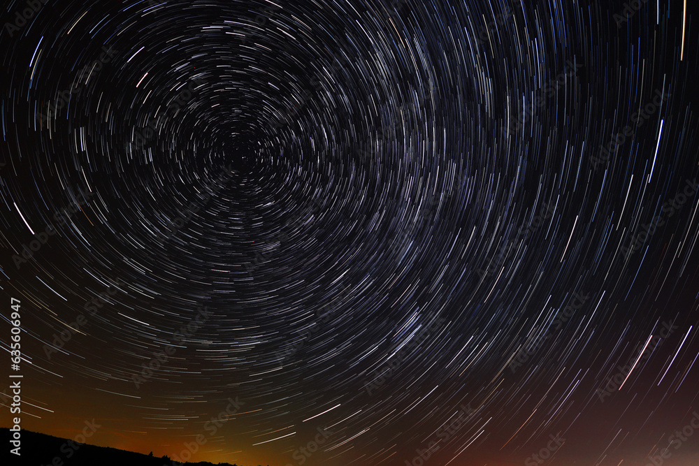 Circular star trails in the sky with a tint of city light from far away on the horizone