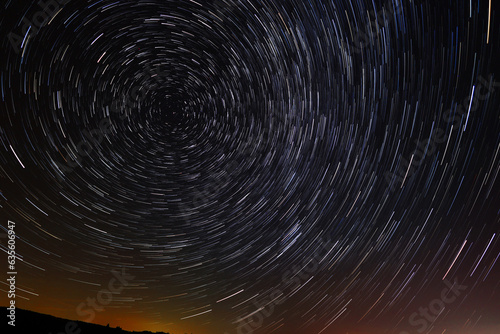 Circular star trails in the sky with a tint of city light from far away on the horizone