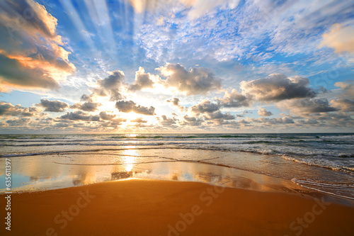 Fototapeta Naklejka Na Ścianę i Meble -  Colorful ocean beach sunrise with deep blue sky and sun rays.