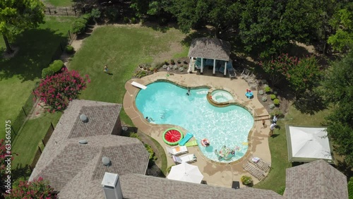 Aerial view of backyard swimming pool party on bright summer afternoon, Texas