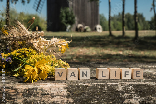 bukiet z kwiatów łąkowych na ławce przy drewnianych kostkach z napisem VAN LIFE