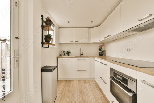 Fotografia a kitchen with wood flooring and white cabinets on the walls, along with an open