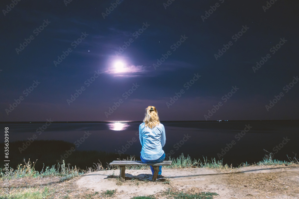 A girl sits by the sea at night under the moon A girl sits by the sea at night under the moon