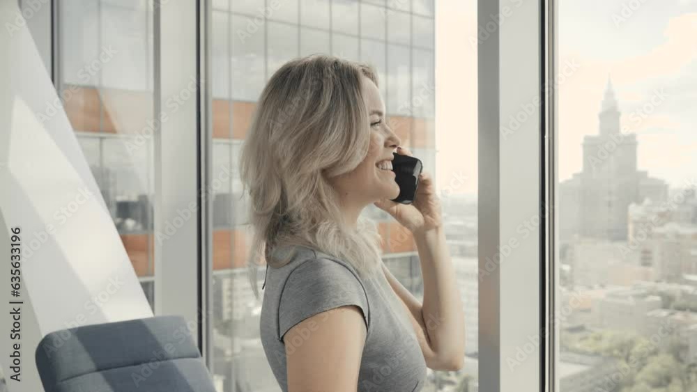 Successful business woman talking on the phone in the office on the background of skyscraper
