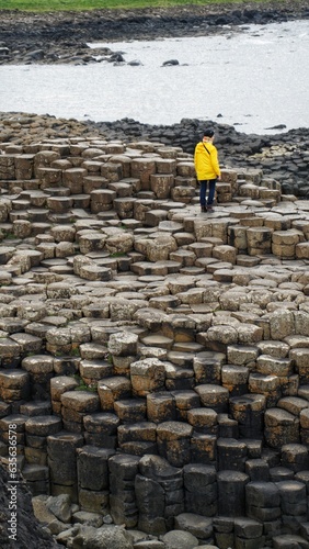 person in yellow jacket walking through hexagonal rocks, giant's causeway