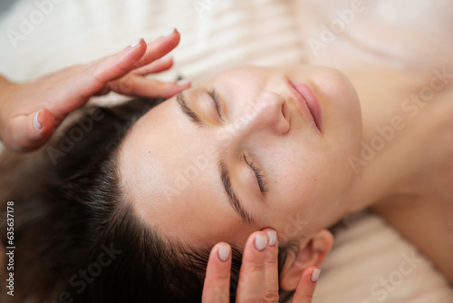 Close up of face of a girl client getting relaxation treating facial massage. Keep skin on face in fit by massage, preventing wrinkles, activating blood circulation on the face