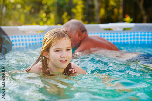Grandpa and granddaughter play and have fun in the pool. 