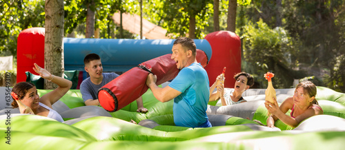 Men and women playing interesting game in adventure park. Different aged people having good time during summertime.