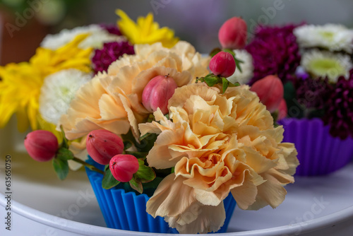 Close up view of a beautiful floral arrangement of colorful flower blossoms arranged in fluted cupcake cups, with defocused background
