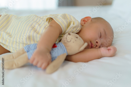Portrait of a newborn boy sleeping and hugging his teddy bear. in the bed in the bedroom at home.