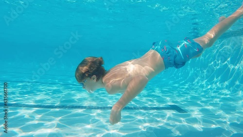 Profile side view of 10 year old boy swimming under water in large lap pool