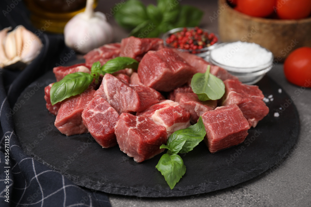 Cut fresh beef meat with basil and spices on brown table, closeup