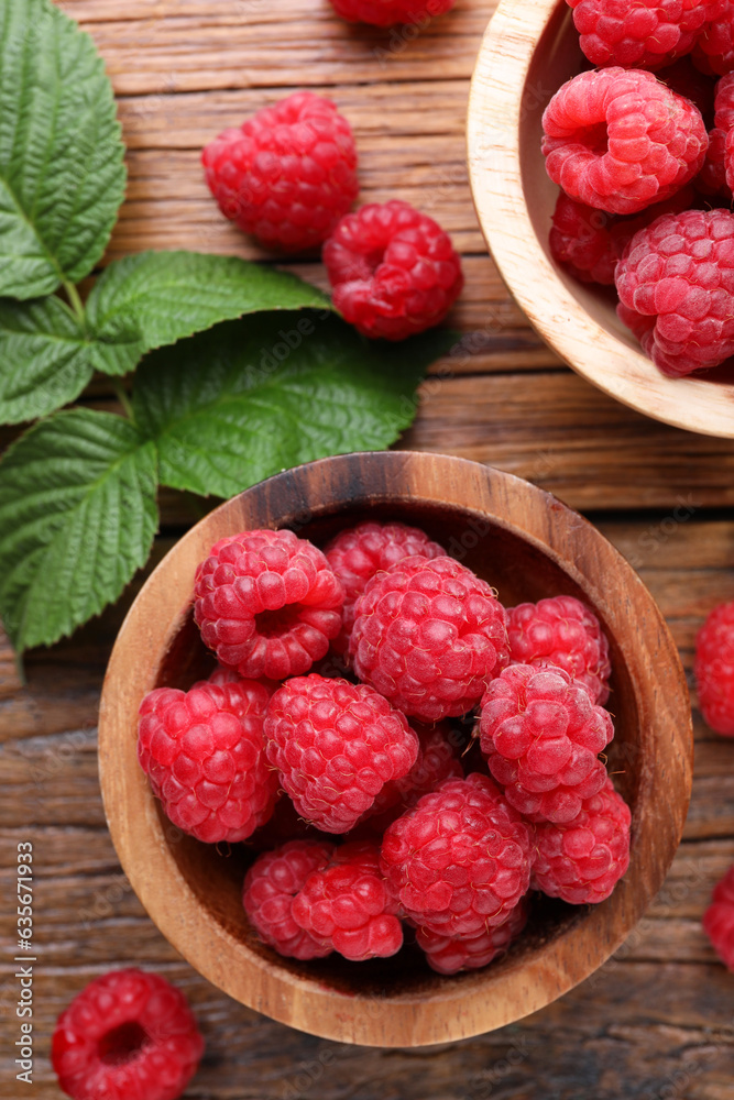 Tasty ripe raspberries and green leaves on wooden table, flat lay Tasty ripe raspberries and green leaves on wooden table, flat lay