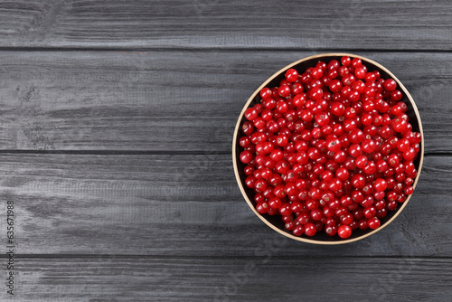 Ripe red currants in bowl on wooden rustic table, top view. Space for text
